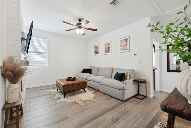 living room featuring visible vents, baseboards, light wood-style floors, and ceiling fan