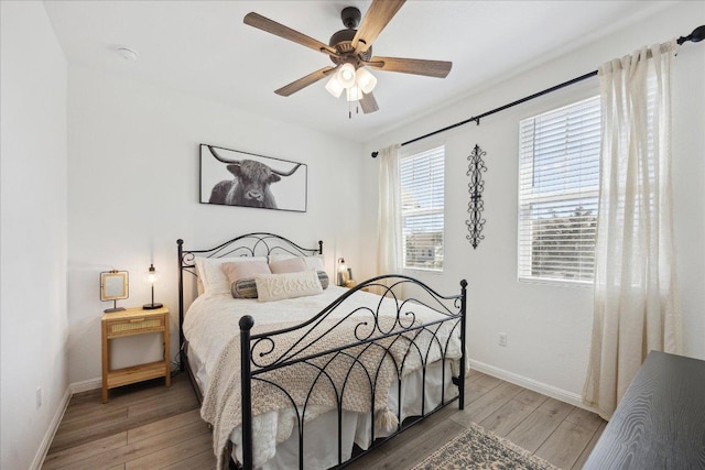 bedroom with a ceiling fan, baseboards, and wood finished floors