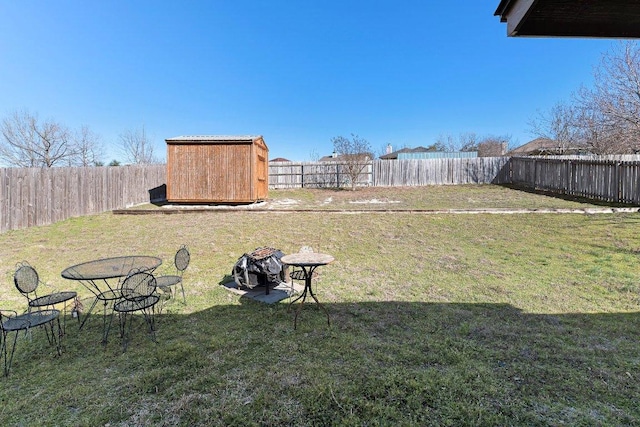 view of yard featuring a fenced backyard, a storage unit, and an outbuilding