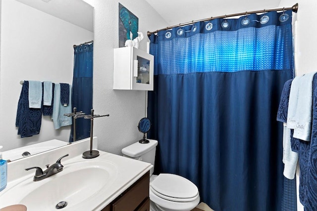 full bath with a textured wall, vanity, and toilet