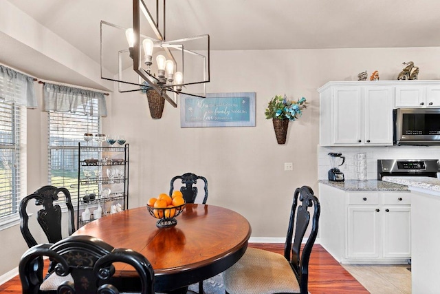 dining room with light wood-style flooring, baseboards, and a chandelier