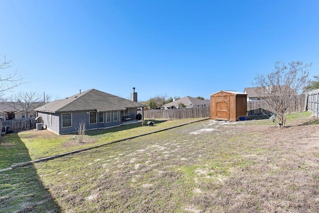 view of yard with central air condition unit, a fenced backyard, an outdoor structure, and a shed