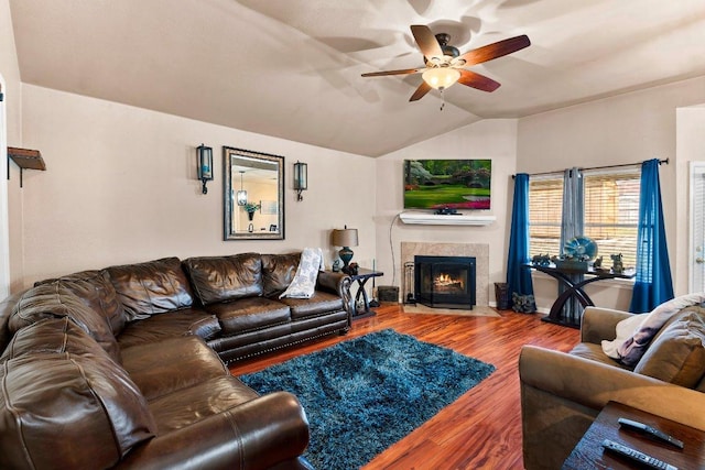 living area featuring a ceiling fan, a fireplace, vaulted ceiling, and wood finished floors