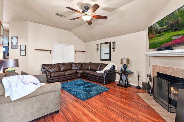 living room with visible vents, a ceiling fan, lofted ceiling, a fireplace with flush hearth, and wood finished floors