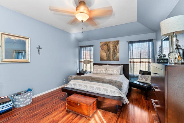 bedroom featuring multiple windows, vaulted ceiling, baseboards, and wood finished floors