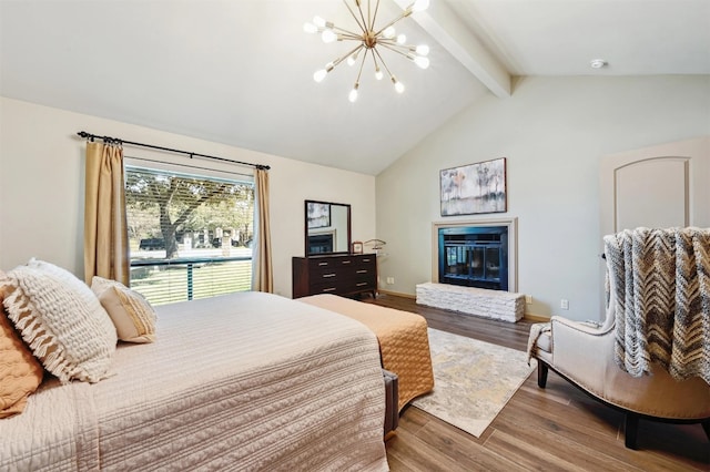 bedroom featuring a glass covered fireplace, lofted ceiling with beams, an inviting chandelier, and wood finished floors