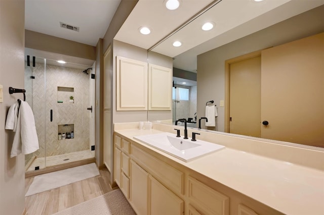 full bath featuring visible vents, wood finished floors, a stall shower, and vanity