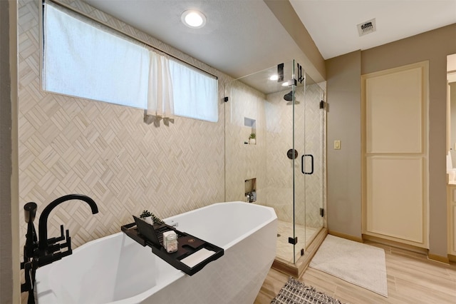 full bathroom with a soaking tub, visible vents, a stall shower, and wood finished floors