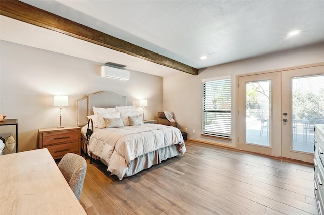 bedroom with a wall mounted AC, light wood-style flooring, access to exterior, french doors, and beamed ceiling