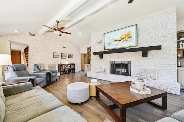 living room featuring wood finished floors, visible vents, beam ceiling, a fireplace, and ceiling fan