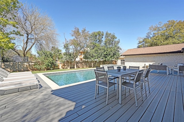 wooden terrace with outdoor dining space, a fenced in pool, and a fenced backyard