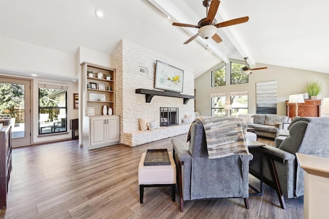 living area with beamed ceiling, visible vents, wood finished floors, a fireplace, and ceiling fan