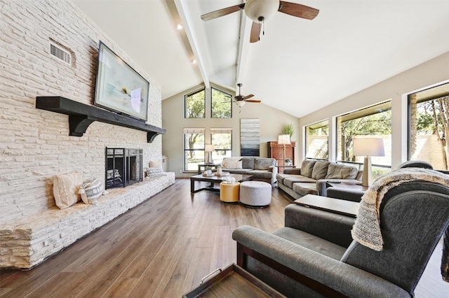 living room featuring beamed ceiling, high vaulted ceiling, wood finished floors, and a fireplace