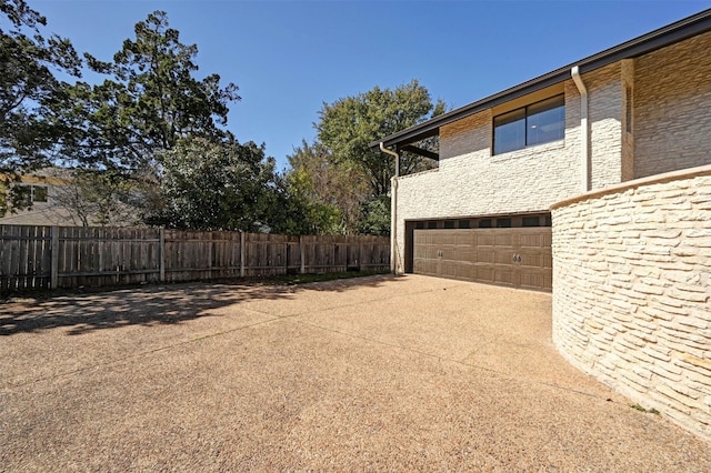 view of yard featuring fence, a garage, and driveway