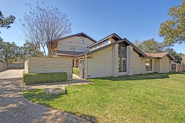 view of side of home with brick siding, a lawn, and fence