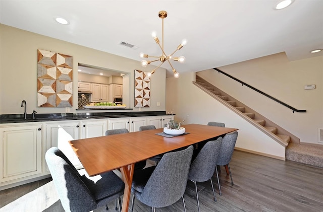 dining room with wood finished floors, visible vents, an inviting chandelier, recessed lighting, and stairs