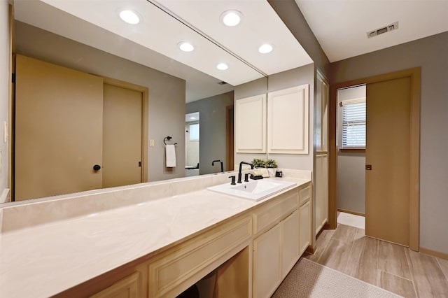 bathroom with visible vents, recessed lighting, vanity, and wood finished floors