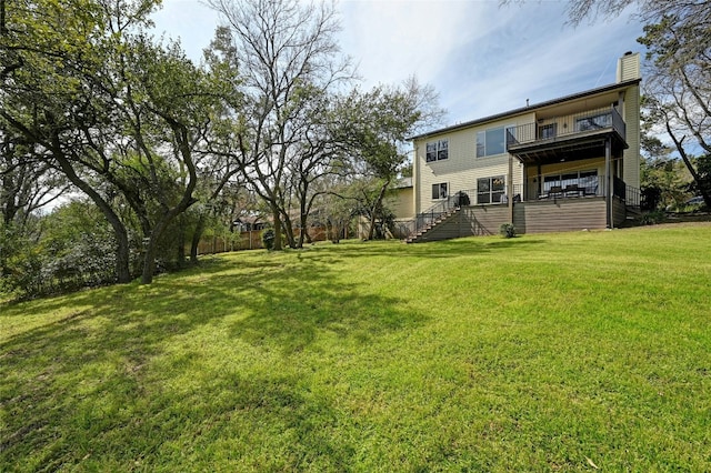 rear view of property featuring a lawn, a chimney, and a balcony