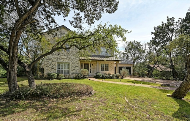 view of front of property with metal roof, an attached garage, stone siding, a front lawn, and a standing seam roof