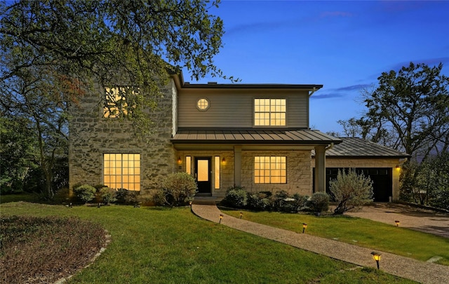 view of front facade featuring a garage, stone siding, metal roof, a standing seam roof, and a yard