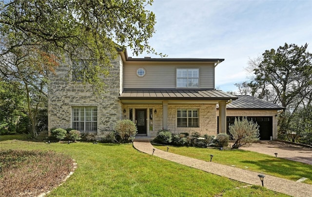 view of front of home featuring stone siding, metal roof, an attached garage, a standing seam roof, and a front yard