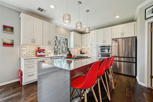 kitchen with appliances with stainless steel finishes, a center island, white cabinets, and visible vents