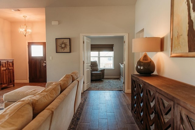 living area with a notable chandelier, baseboards, and dark wood finished floors