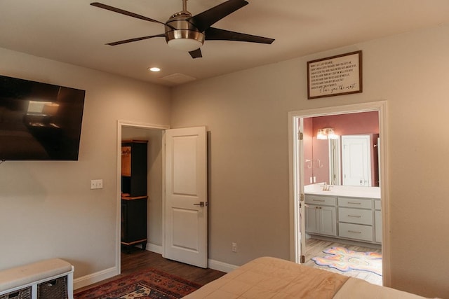 bedroom featuring baseboards, recessed lighting, connected bathroom, a sink, and wood finished floors