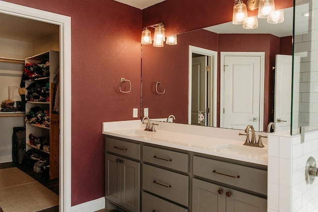 full bath with a sink, a spacious closet, baseboards, and double vanity