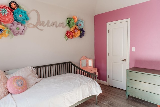 bedroom with baseboards, vaulted ceiling, and wood finished floors