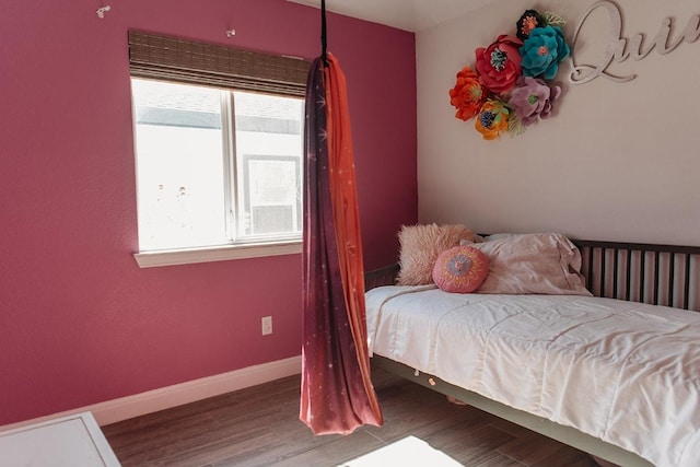 bedroom with wood finished floors, baseboards, and multiple windows
