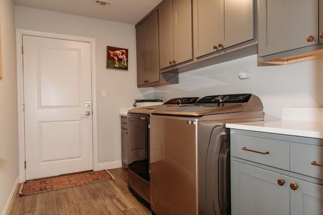 clothes washing area with washer and dryer, baseboards, cabinet space, and light wood finished floors