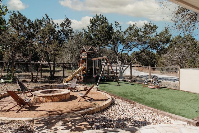 view of yard featuring an outdoor fire pit, fence, and playground community