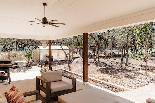 view of patio with a trampoline, an outdoor structure, a fenced backyard, and a ceiling fan