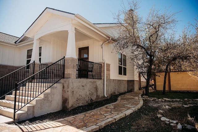 view of side of property featuring stone siding and fence