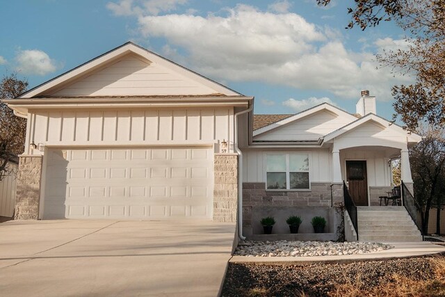 ranch-style house with stone siding, a garage, a chimney, board and batten siding, and concrete driveway