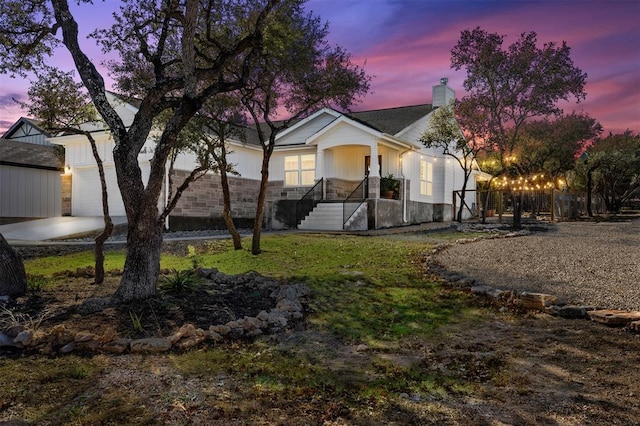 view of front of house with a garage, stone siding, a chimney, and concrete driveway