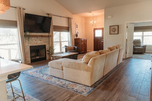 living room with lofted ceiling, a notable chandelier, a fireplace, and dark wood-type flooring