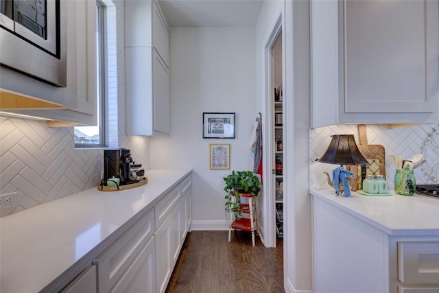 kitchen featuring dark wood finished floors, white cabinets, light countertops, and baseboards