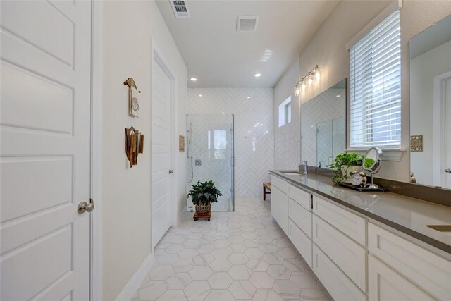 bathroom featuring double vanity, visible vents, a stall shower, and a sink