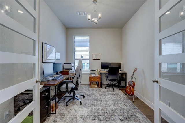 office area with a notable chandelier, wood finished floors, visible vents, and baseboards