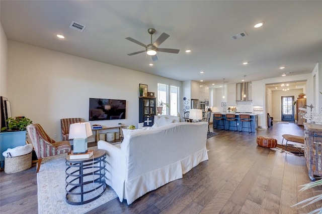 living area with visible vents, a healthy amount of sunlight, and wood finished floors