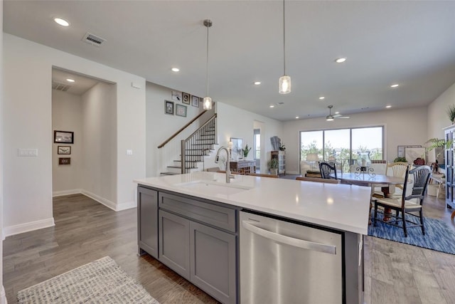 kitchen with recessed lighting, gray cabinets, a sink, stainless steel dishwasher, and light wood-type flooring