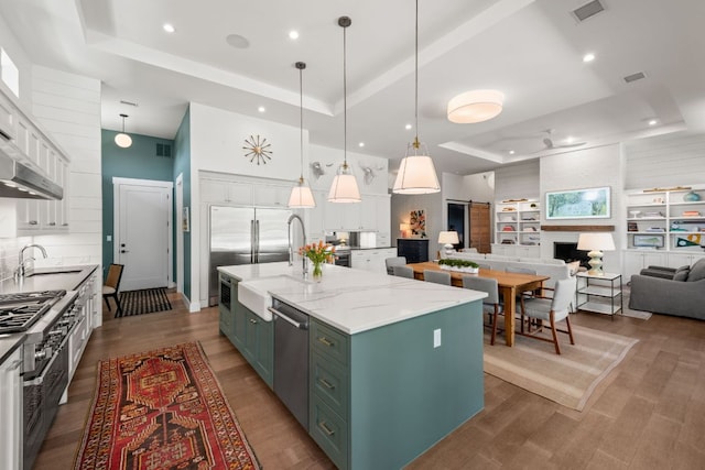 kitchen featuring a sink, green cabinets, a raised ceiling, and white cabinets