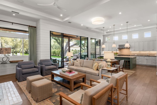 living area featuring a tray ceiling, a healthy amount of sunlight, and visible vents