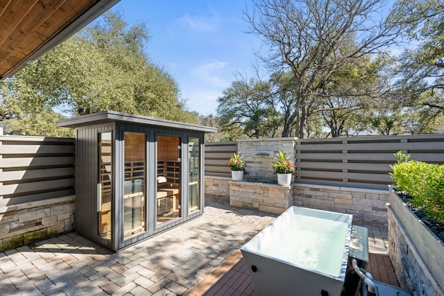 deck with a patio, an outbuilding, and a fenced backyard