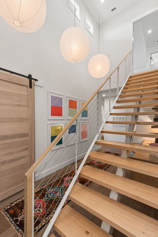 stairway featuring a barn door, visible vents, and a towering ceiling