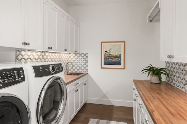 laundry room with dark wood-type flooring, independent washer and dryer, a sink, cabinet space, and baseboards