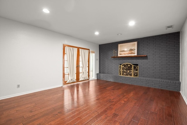 611 Virginia Dr, Round Rock, TX 78664 - unfurnished living room featuring a brick fireplace, wood finished floors, baseboards, recessed lighting, and brick wall