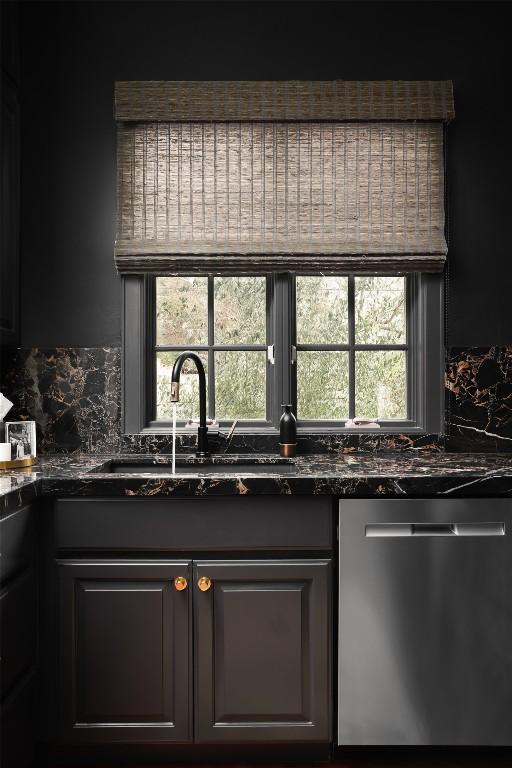 kitchen featuring a sink, stainless steel dishwasher, a healthy amount of sunlight, and dark stone countertops